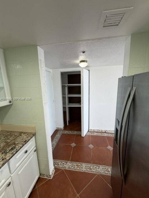 7601 E Treasure Drive, #2417, North Bay Village, North Bay Village, FL 33141 Kitchen area featuring patterned tile flooring with decorative border, white cabinetry, stone-finish countertops, built-in pantry with shelving, and flush-mount ceiling lighting