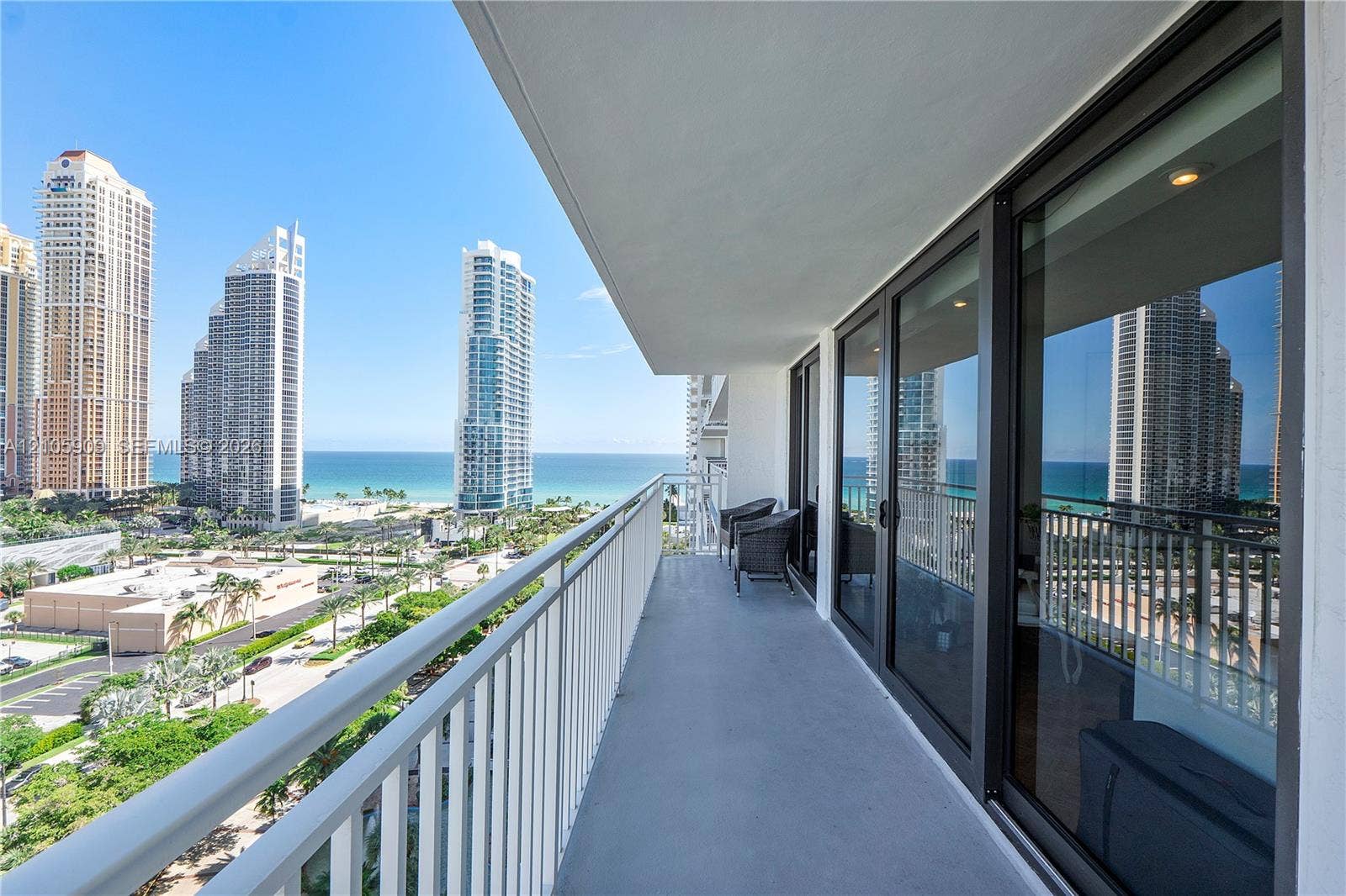 Covered balcony featuring metal railings and floor-to-ceiling glass sliding doors