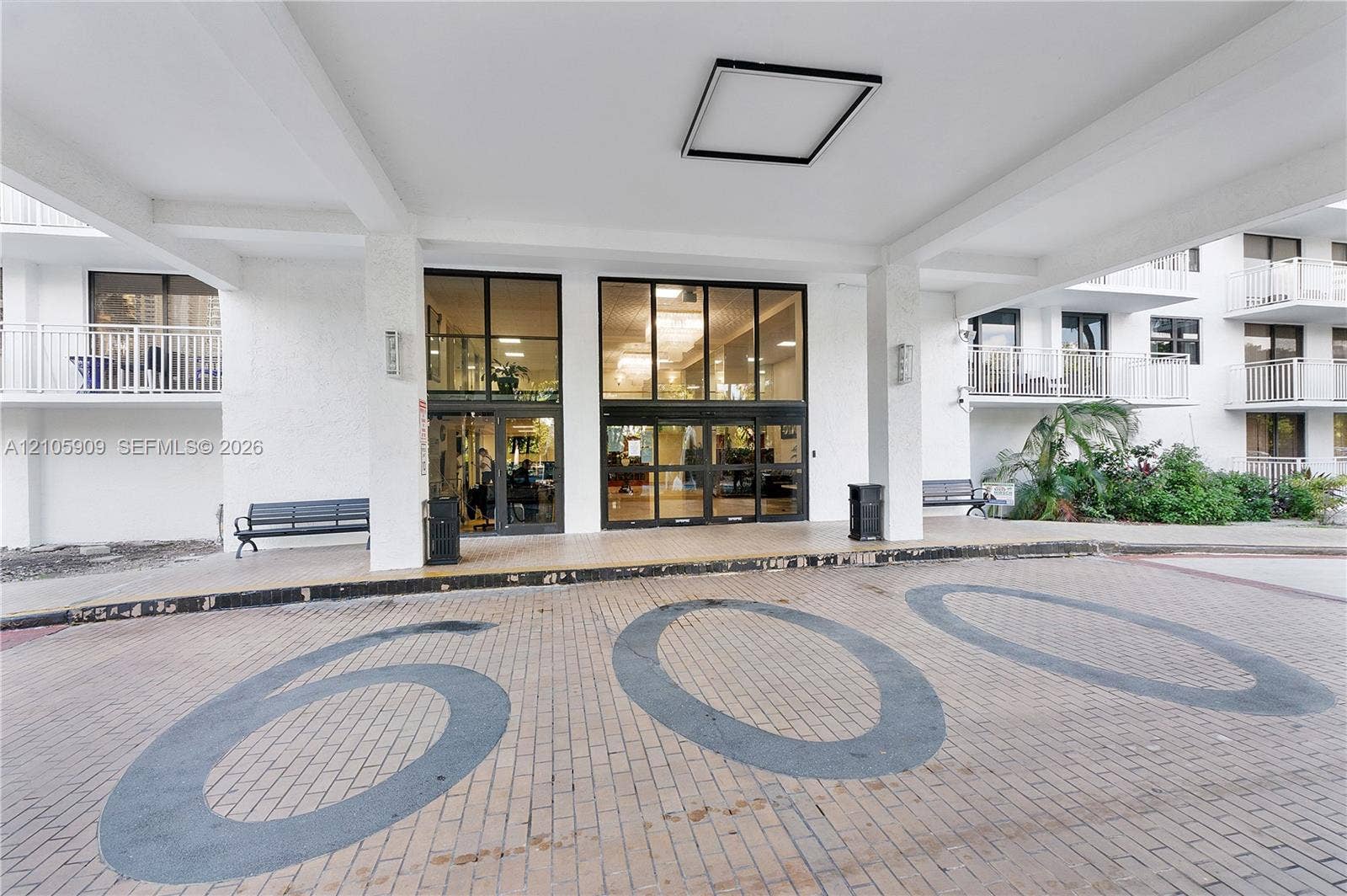 Covered porte-cochre entry featuring brick paving and glass-paneled double doors