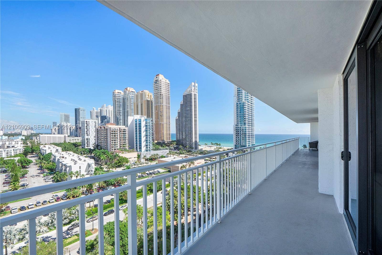 Expansive covered balcony with a white metal railing and concrete flooring