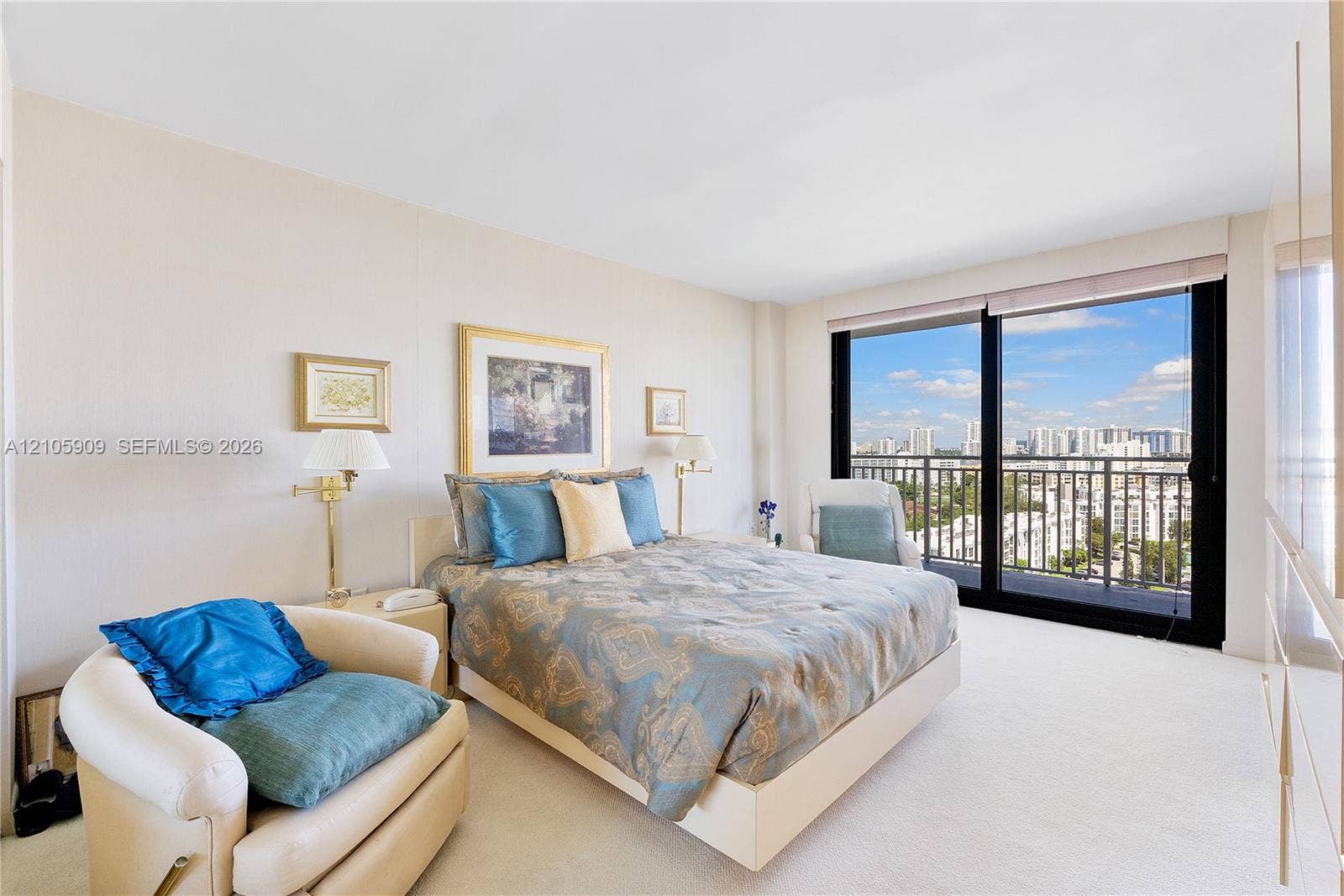 Floor-to-ceiling glass sliding doors, private balcony with metal railing, and neutral wall-to-wall carpeting