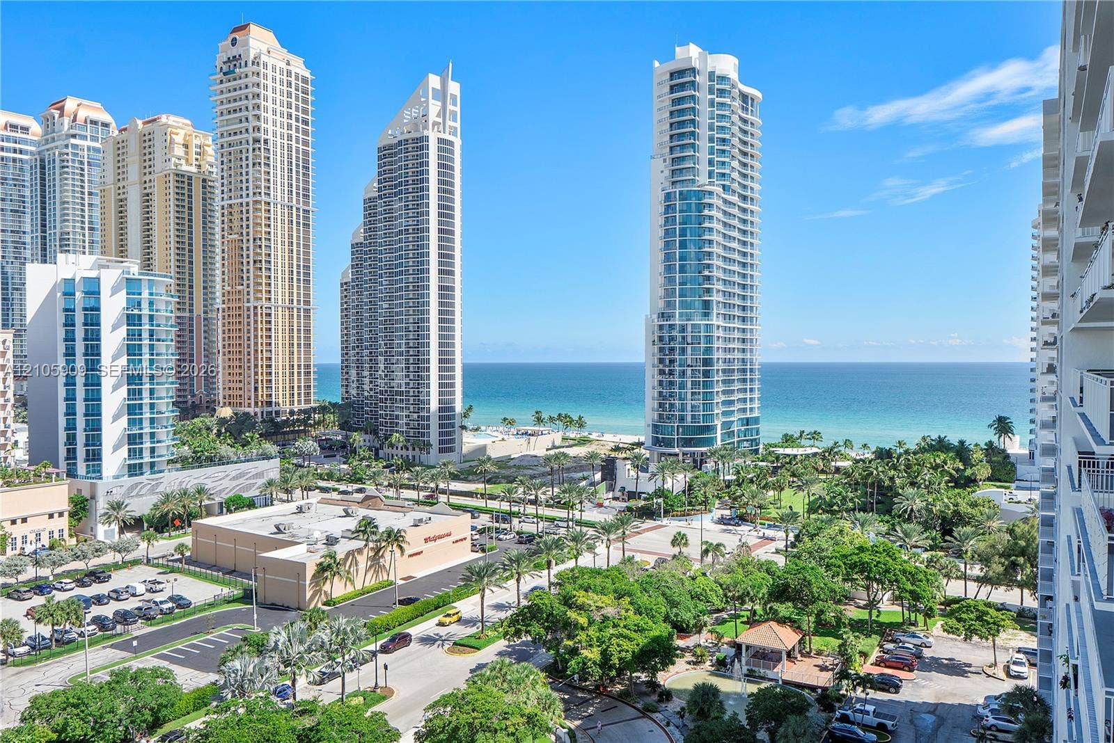 High-rise urban landscape featuring oceanfront proximity, expansive coastal horizon, mature palm trees, and glass-paneled architectural exteriors