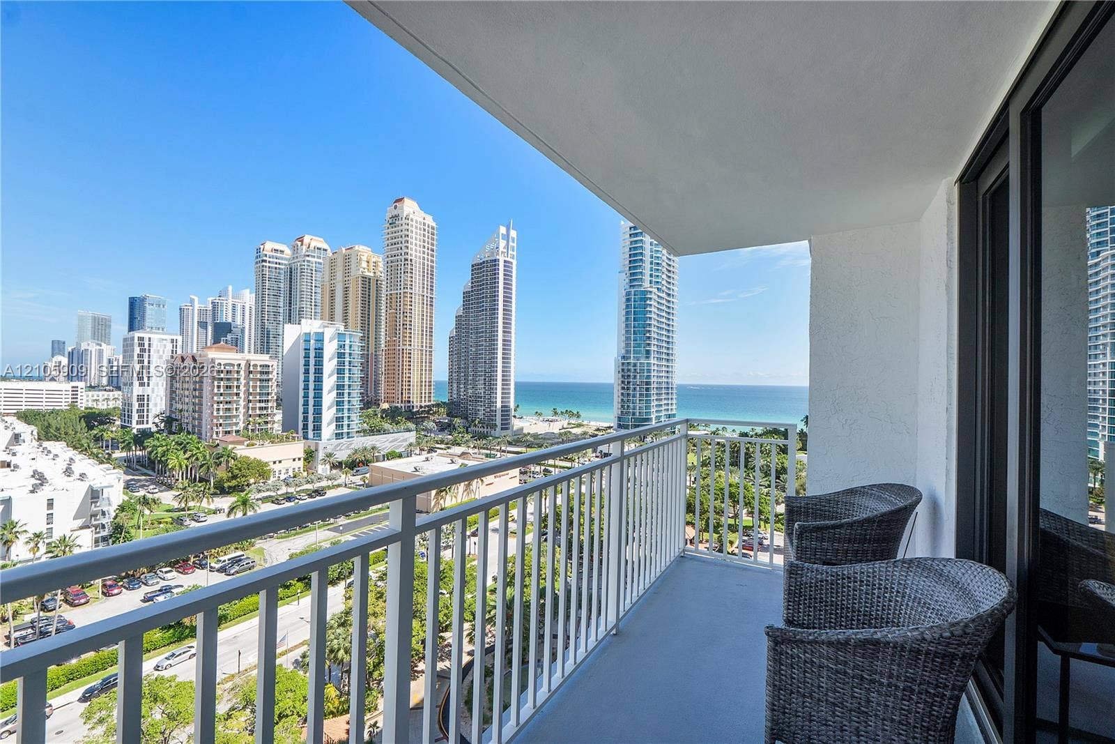 Private balcony featuring a painted concrete floor, white metal railing, and an expansive skyline and ocean backdrop
