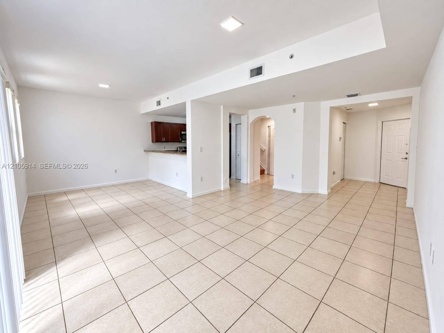 11102 NW 83rd Street, #216, Doral, FL 33178 Open-concept interior featuring light-toned tile flooring, recessed lighting, a breakfast bar, and architectural arched detailing