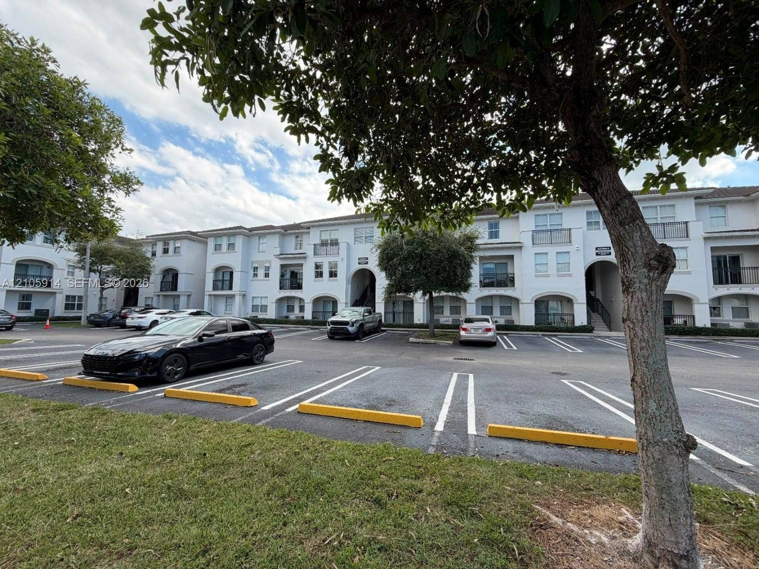 11102 NW 83rd Street, #216, Doral, FL 33178 Multi-story residential complex featuring arched architectural details, private balconies, paved parking, and manicured landscaping