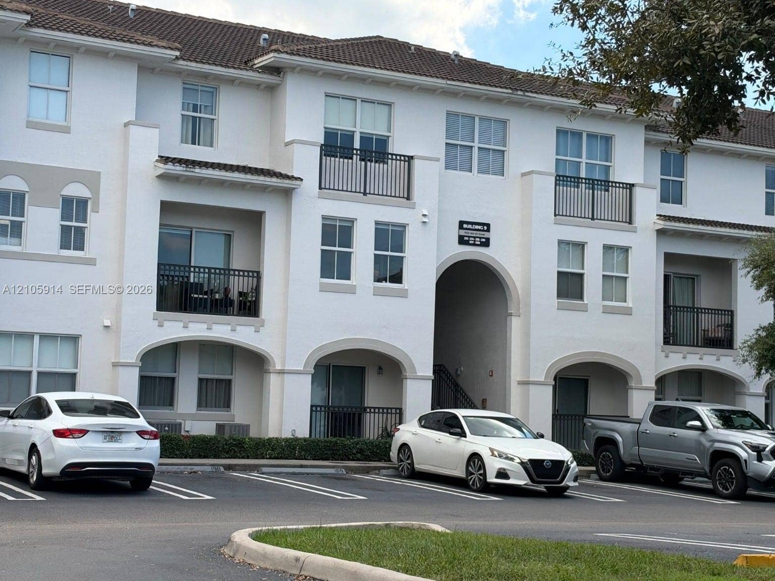 11102 NW 83rd Street, #216, Doral, FL 33178 Multi-story stucco exterior featuring arched entryways, tile roof, and private railed balconies