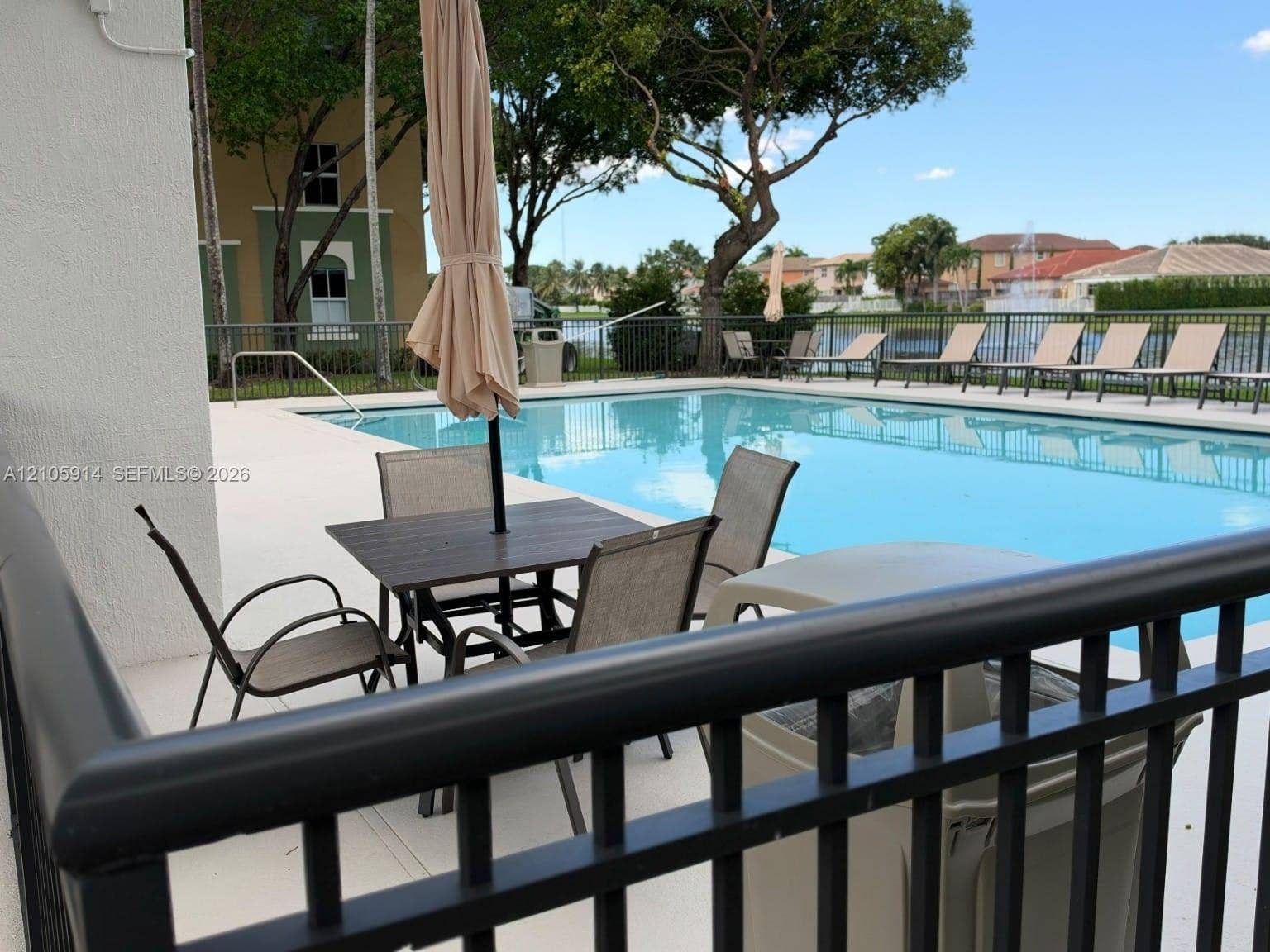 11102 NW 83rd Street, #216, Doral, FL 33178 In-ground swimming pool with light-colored concrete decking, metal perimeter fencing, and water feature