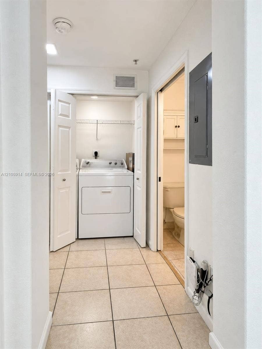 11102 NW 83rd Street, #216, Doral, FL 33178 Laundry area featuring tile flooring, built-in wire shelving, and bi-fold closet doors