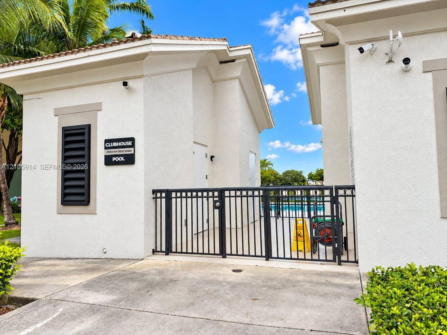 11102 NW 83rd Street, #216, Doral, FL 33178 Stucco exterior clubhouse featuring a gated entry, tiled roof, and decorative louvered shutter