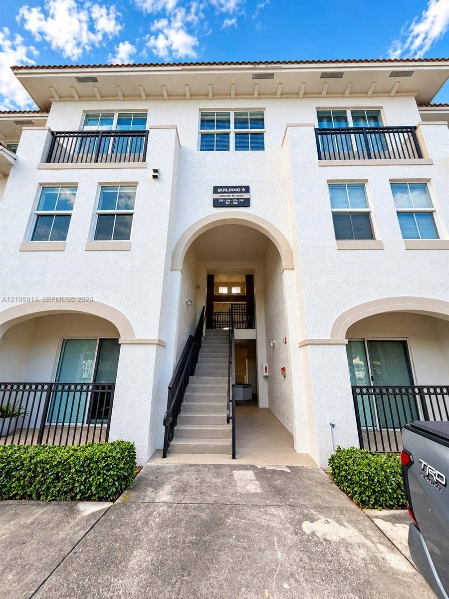 11102 NW 83rd Street, #216, Doral, FL 33178 Stucco exterior featuring arched entryways, multi-level balconies with black metal railings, and a tiled roofline