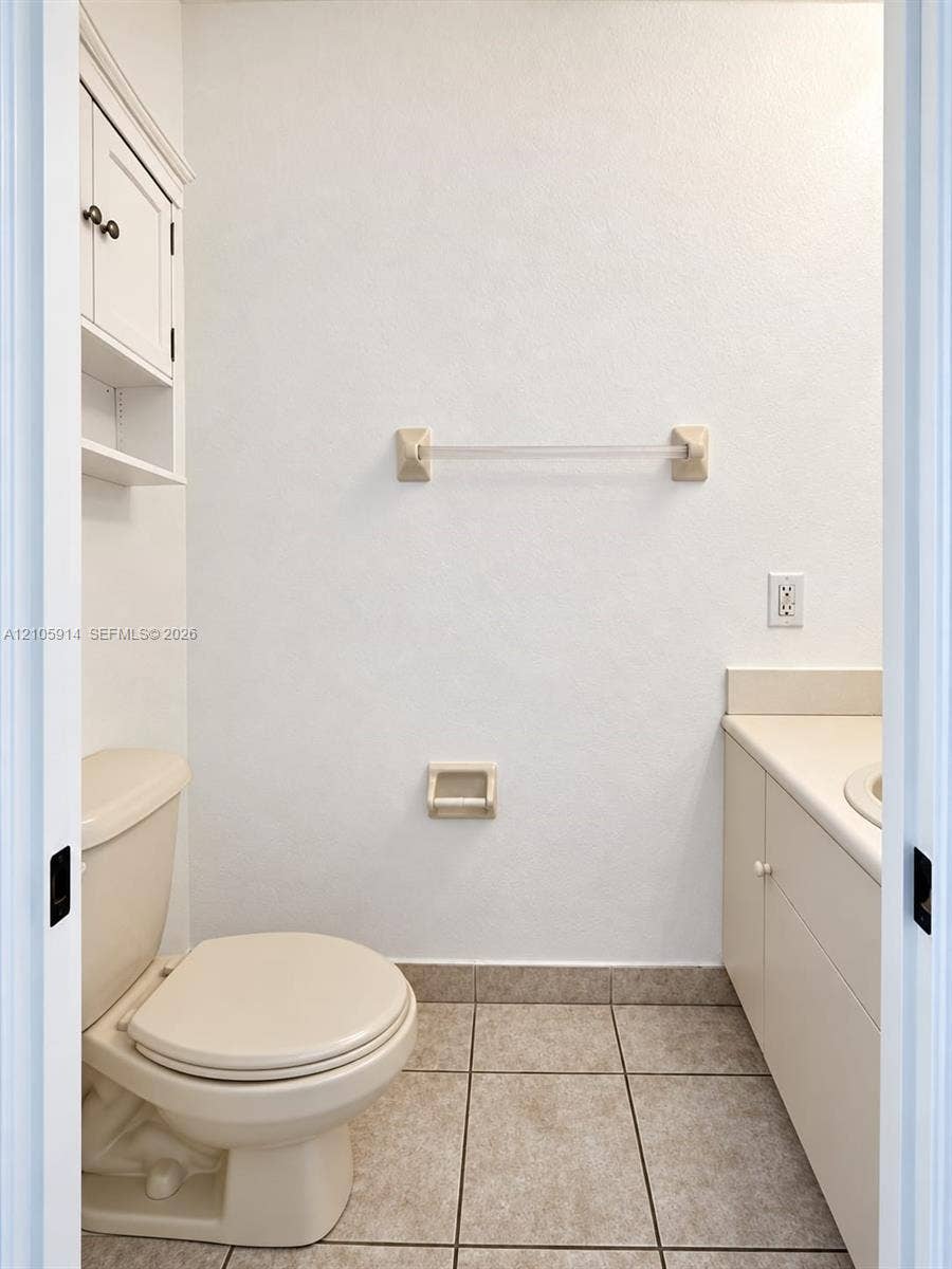 11102 NW 83rd Street, #216, Doral, FL 33178 Neutral-toned bathroom featuring tile flooring, built-in cabinetry with a vanity countertop, and wall-mounted storage shelving