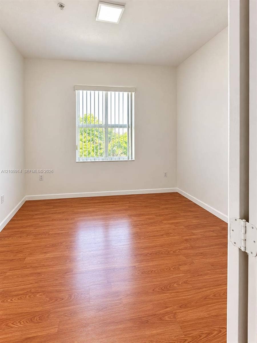 11102 NW 83rd Street, #216, Doral, FL 33178 Interior space featuring wood-finish flooring, a neutral color palette, a rectangular window with vertical blinds, and a recessed ceiling light fixture