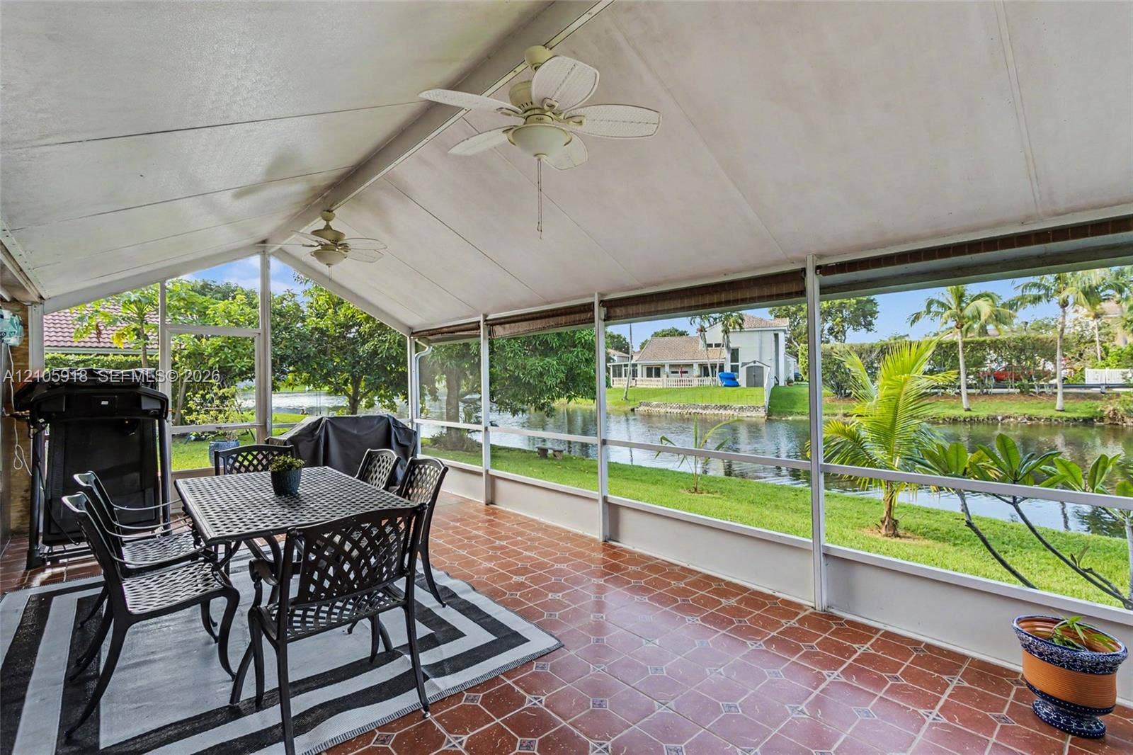Screened lanai featuring tiled flooring, a vaulted ceiling, dual overhead ceiling fans, and expansive water frontage