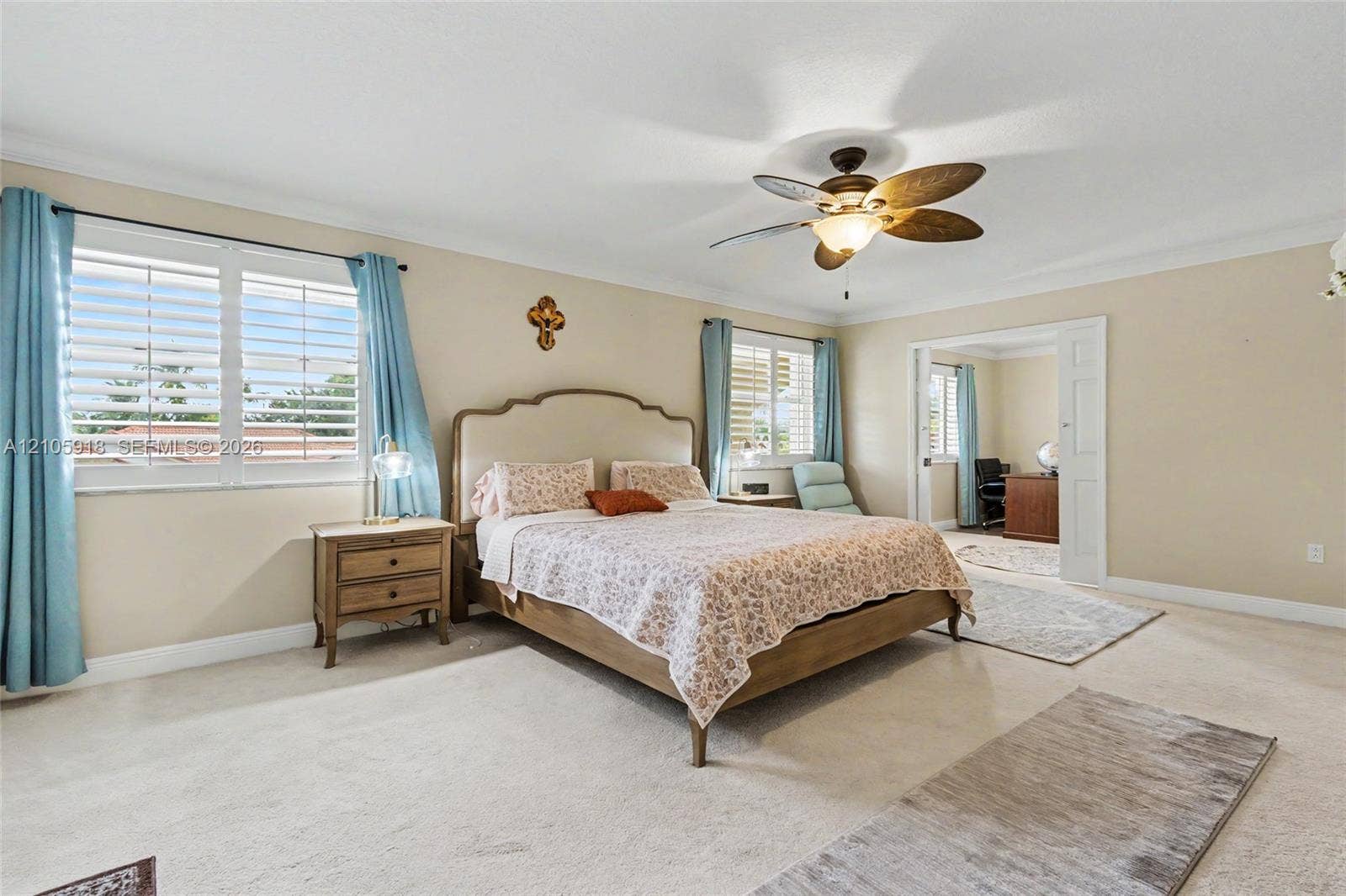Bedroom featuring plantation shutters, neutral wall coloring, ceiling fan with integrated lighting, and white paneled sliding doors