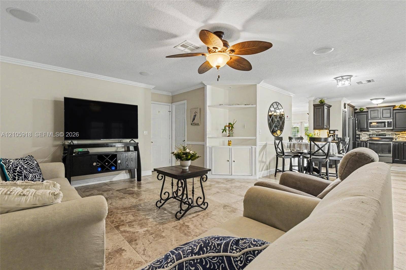 Open-concept interior featuring large-format tile flooring, a ceiling fan with integrated lighting, recessed lighting, and built-in cabinetry