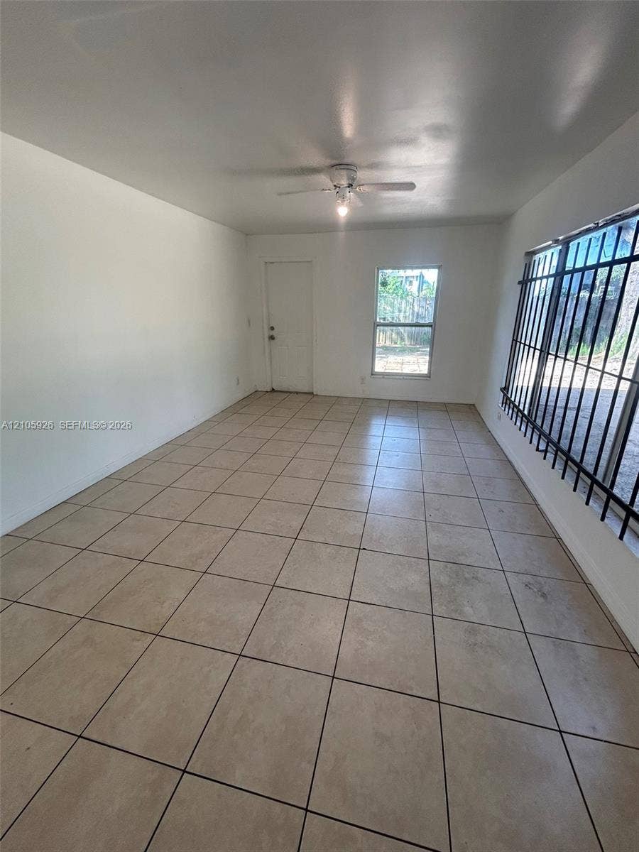 1601 W Avenue H W, Riviera Beach, Riviera Beach, FL 33404 Interior space featuring ceramic tile flooring, a ceiling-mounted fan with light fixture, and windows equipped with metal security bars