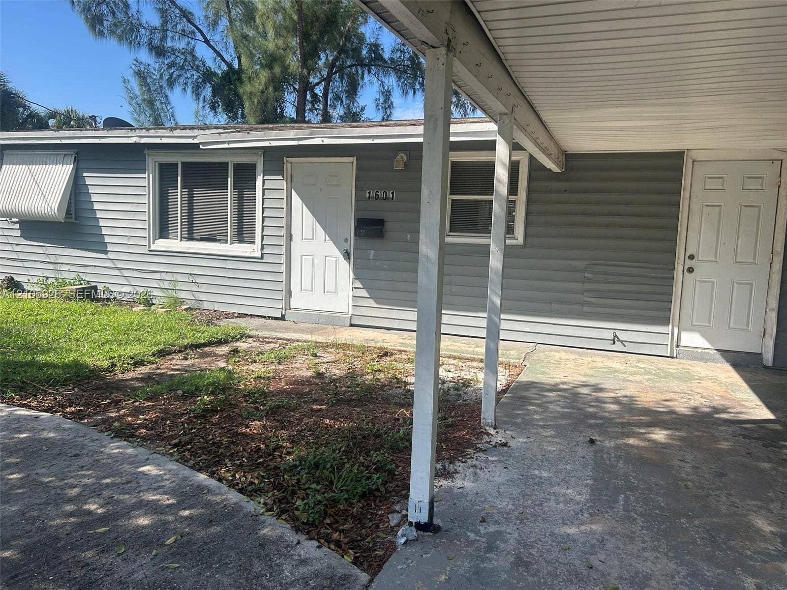 1601 W Avenue H W, Riviera Beach, Riviera Beach, FL 33404 Horizontal siding exterior featuring a covered carport, two entry doors, and a metal window awning