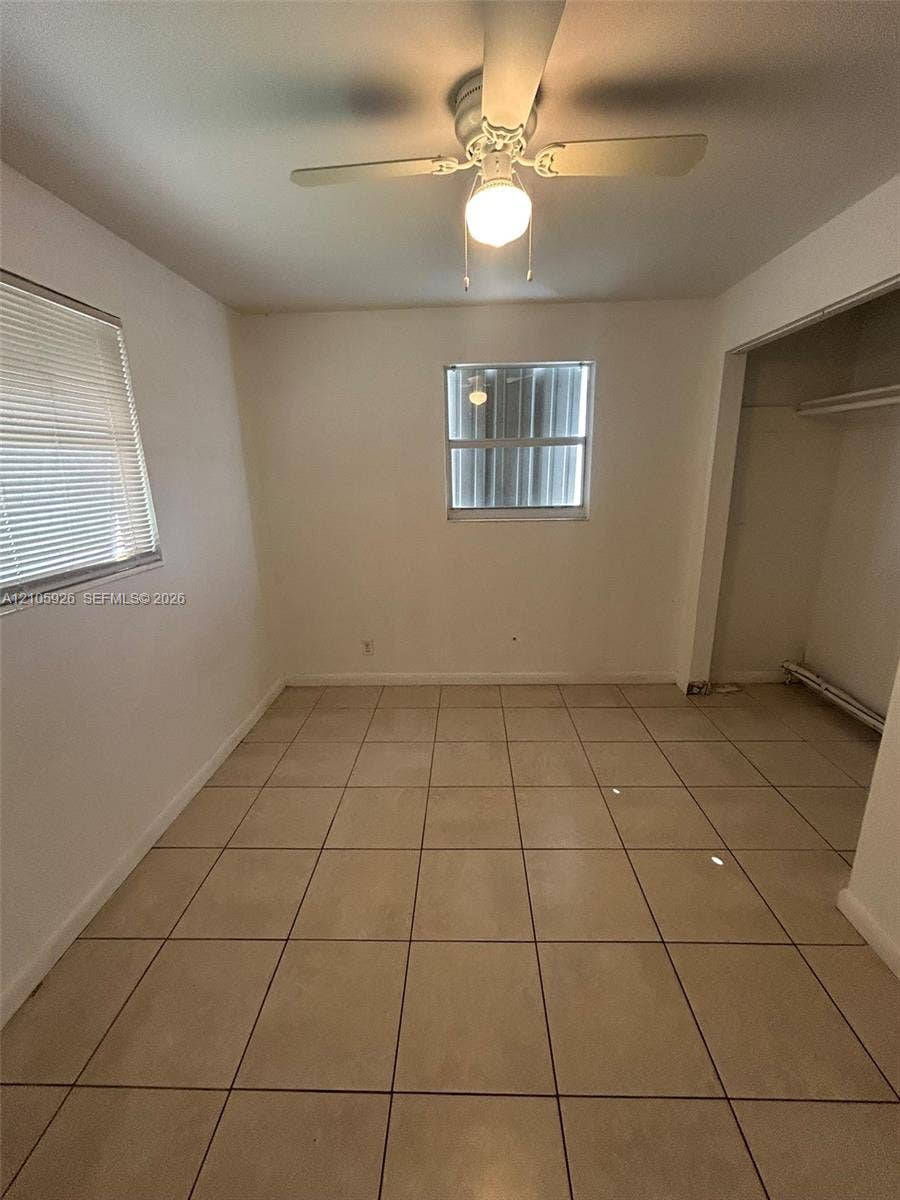 1601 W Avenue H W, Riviera Beach, Riviera Beach, FL 33404 Room featuring ceramic tile flooring, dual windows with blinds, a ceiling fan with integrated lighting, and a closet with a built-in rod