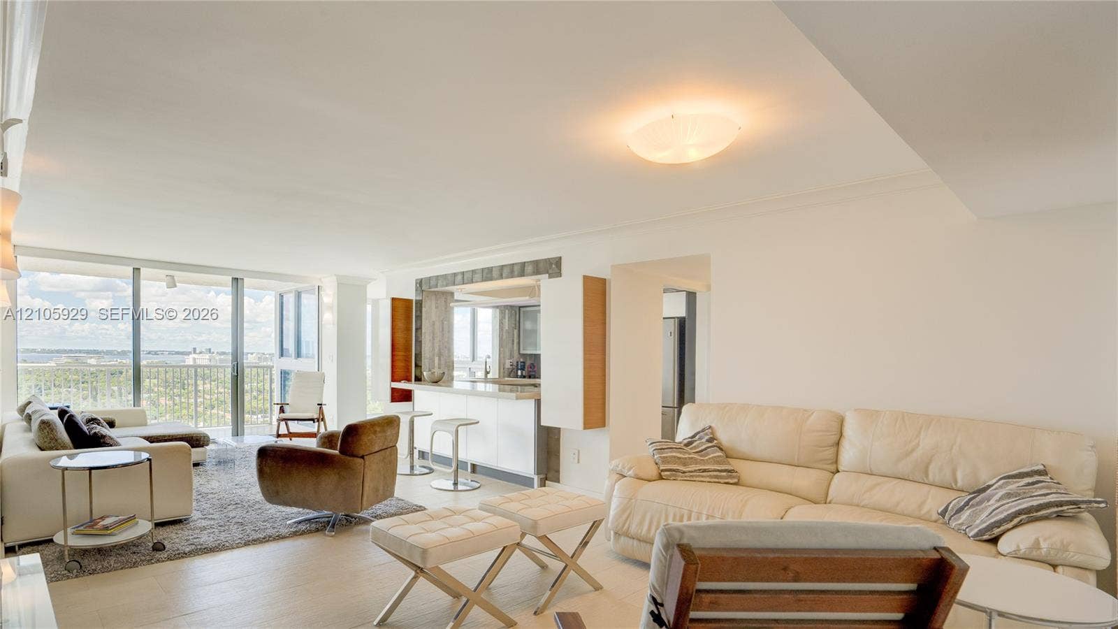 2655 Collins Avenue, #2301, Miami Beach, FL 33140 Open-concept interior featuring light-toned flooring, floor-to-ceiling glass sliding doors, and a kitchen area with a built-in counter