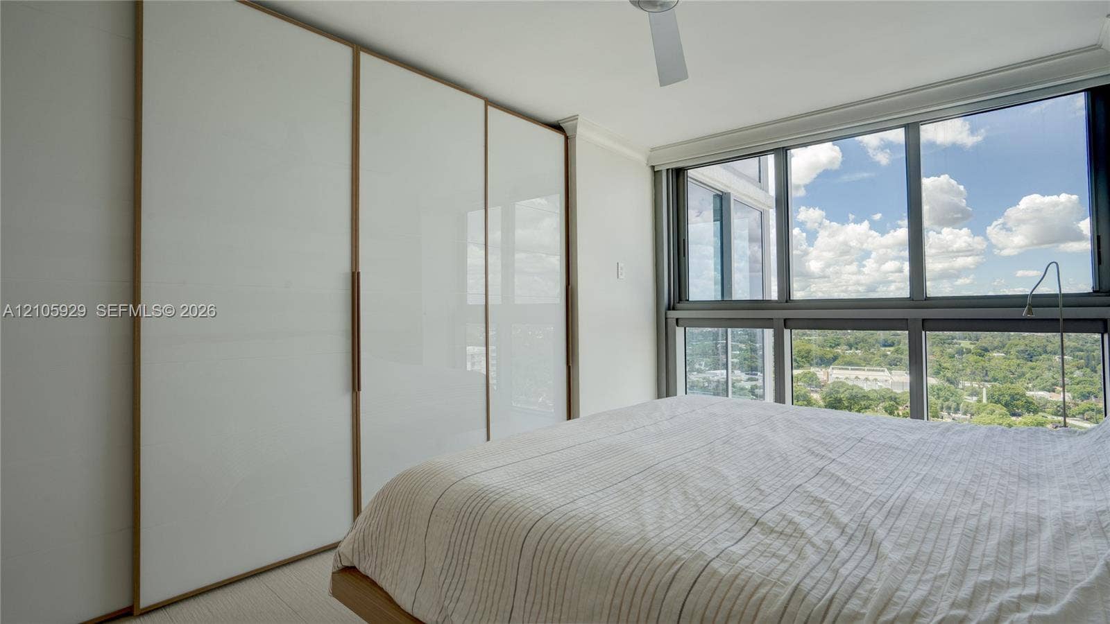 2655 Collins Avenue, #2301, Miami Beach, FL 33140 Floor-to-ceiling windows, built-in floor-to-ceiling closets with white panels and trim, and a ceiling fan
