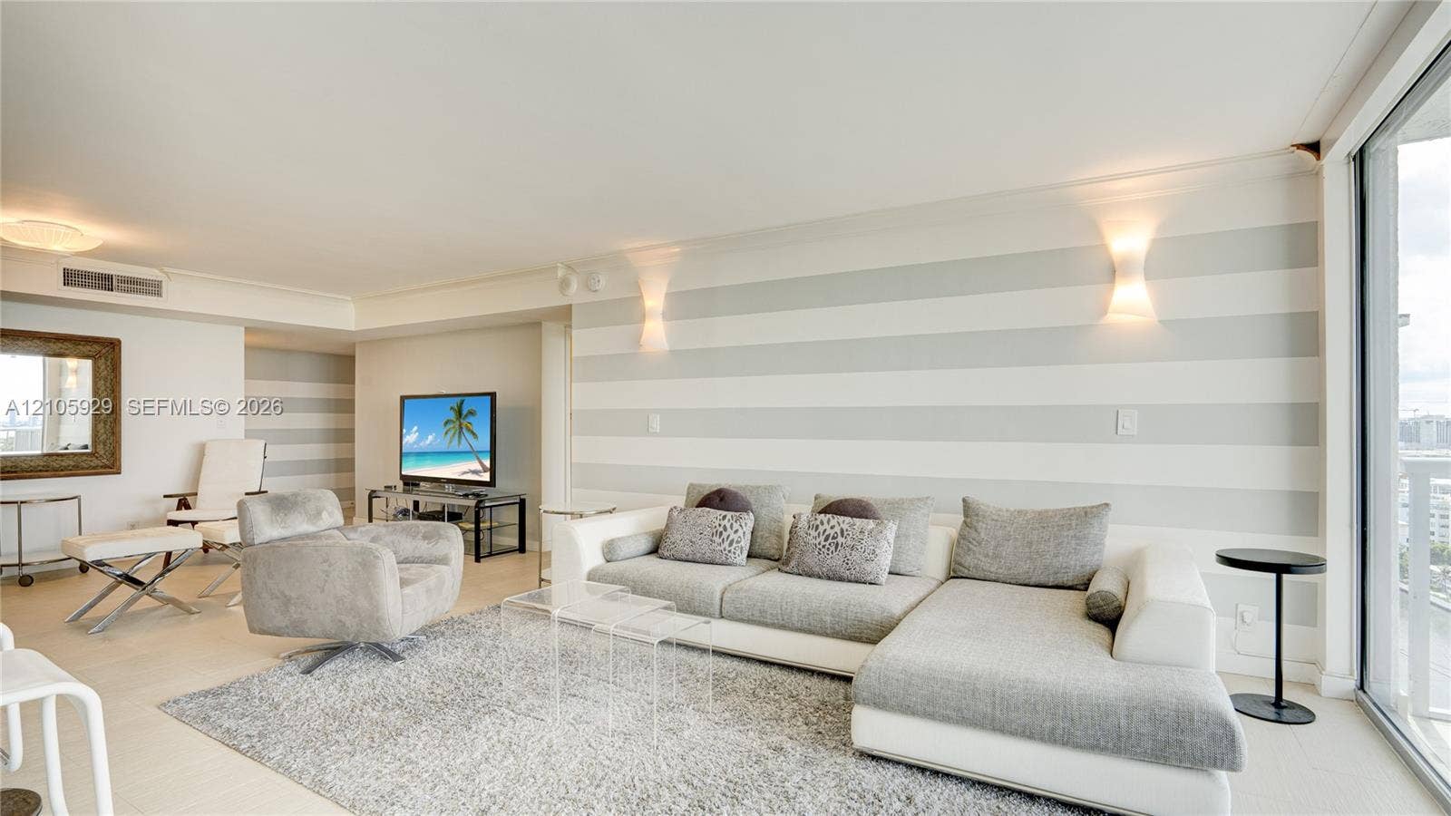 2655 Collins Avenue, #2301, Miami Beach, FL 33140 Spacious room featuring neutral-toned horizontal wall stripes, floor-to-ceiling glass sliding doors, and recessed wall-mounted lighting