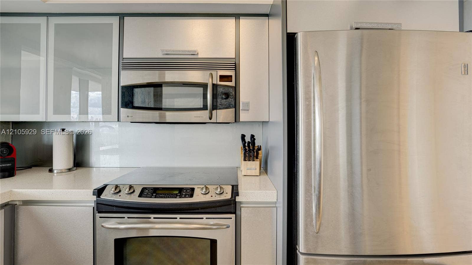2655 Collins Avenue, #2301, Miami Beach, FL 33140 Kitchen featuring high-gloss cabinetry, stone-finish countertops, stainless steel appliances, and a smooth-top electric range