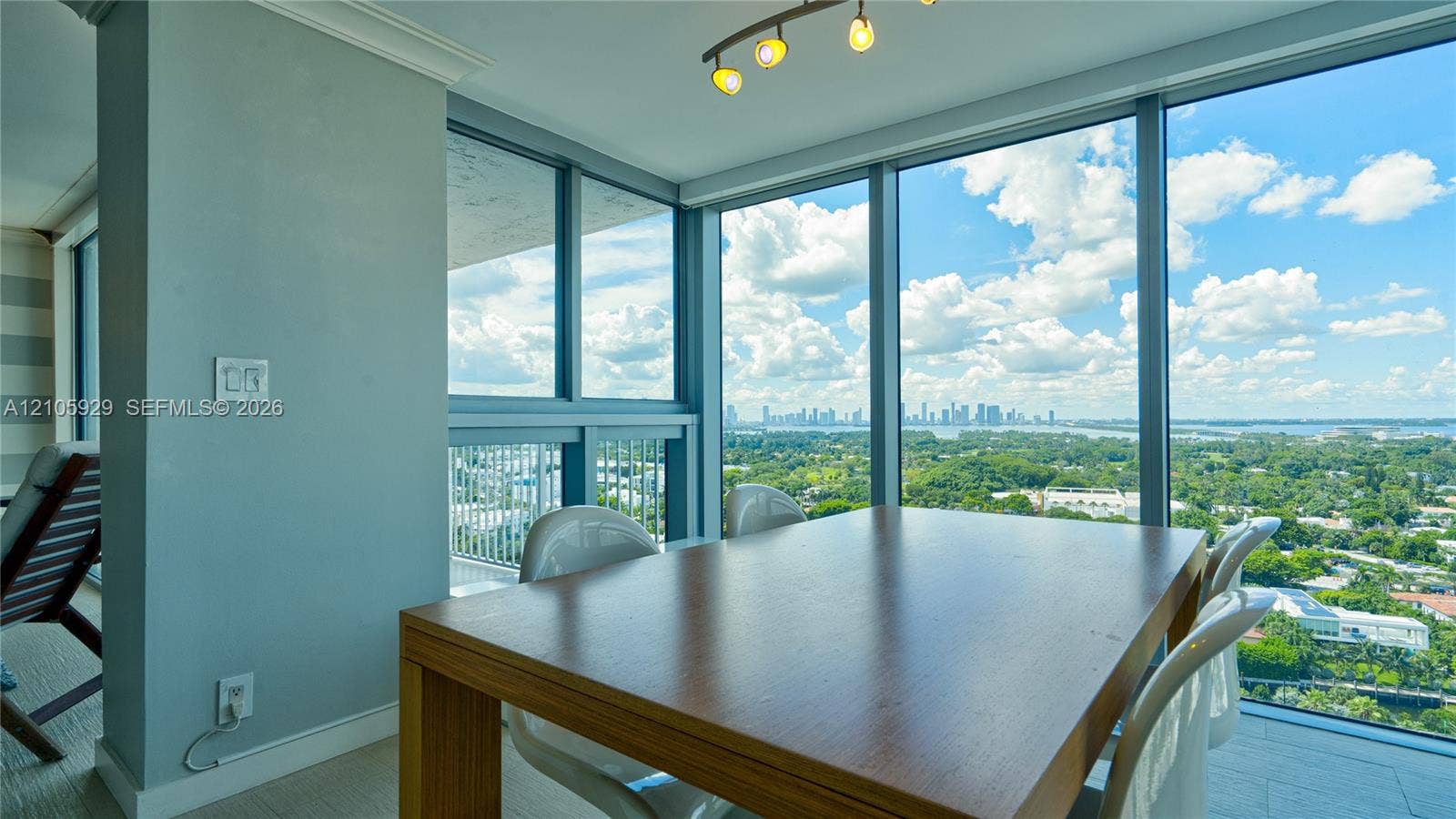 2655 Collins Avenue, #2301, Miami Beach, FL 33140 Floor-to-ceiling windows featuring panoramic city and water vistas, crown molding, and a modern multi-bulb linear light fixture