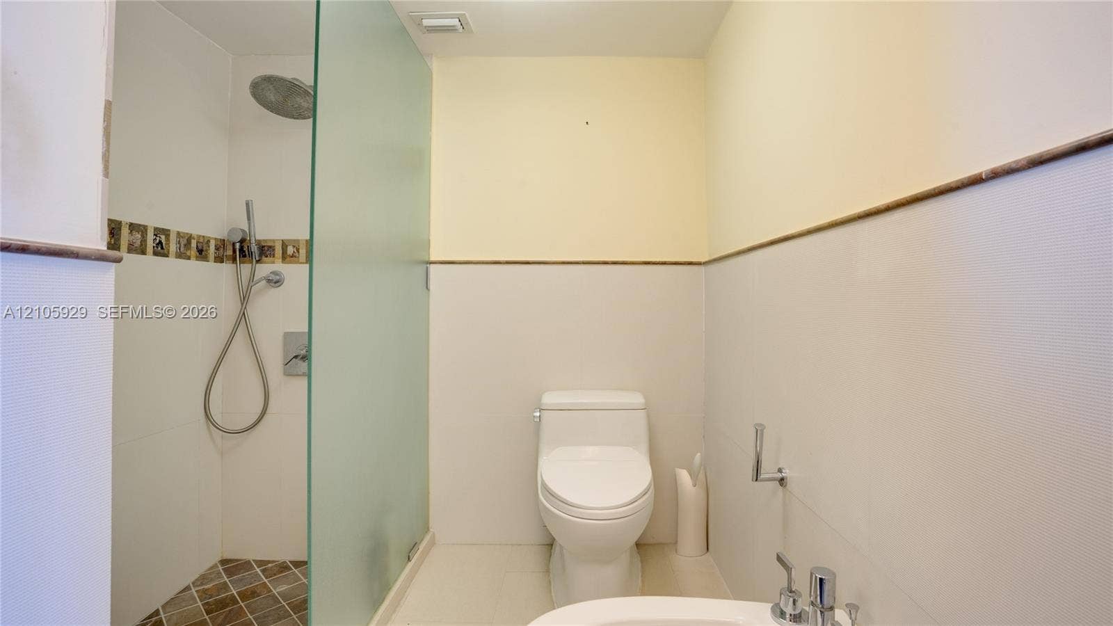 2655 Collins Avenue, #2301, Miami Beach, FL 33140 Walk-in shower featuring a frosted glass partition, rainfall showerhead, and tiled flooring, accompanied by a low-profile toilet and bidet