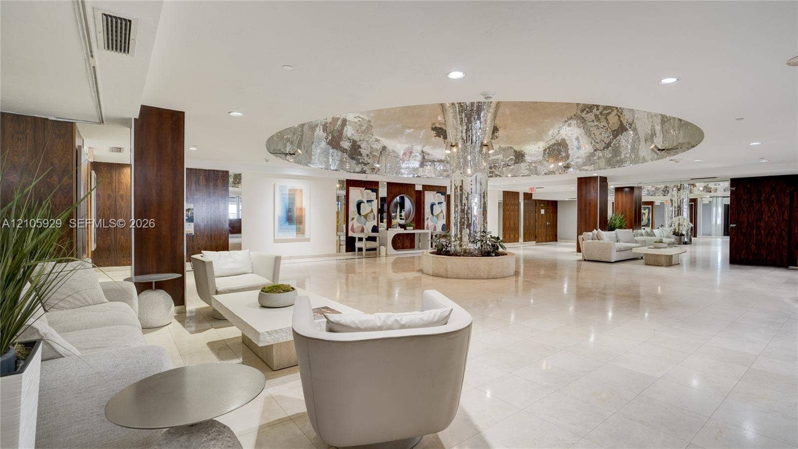 2655 Collins Avenue, #2301, Miami Beach, FL 33140 Expansive lobby featuring polished stone flooring, dark wood-finished paneling, recessed lighting, and a prominent central circular ceiling feature with a reflective metallic finish