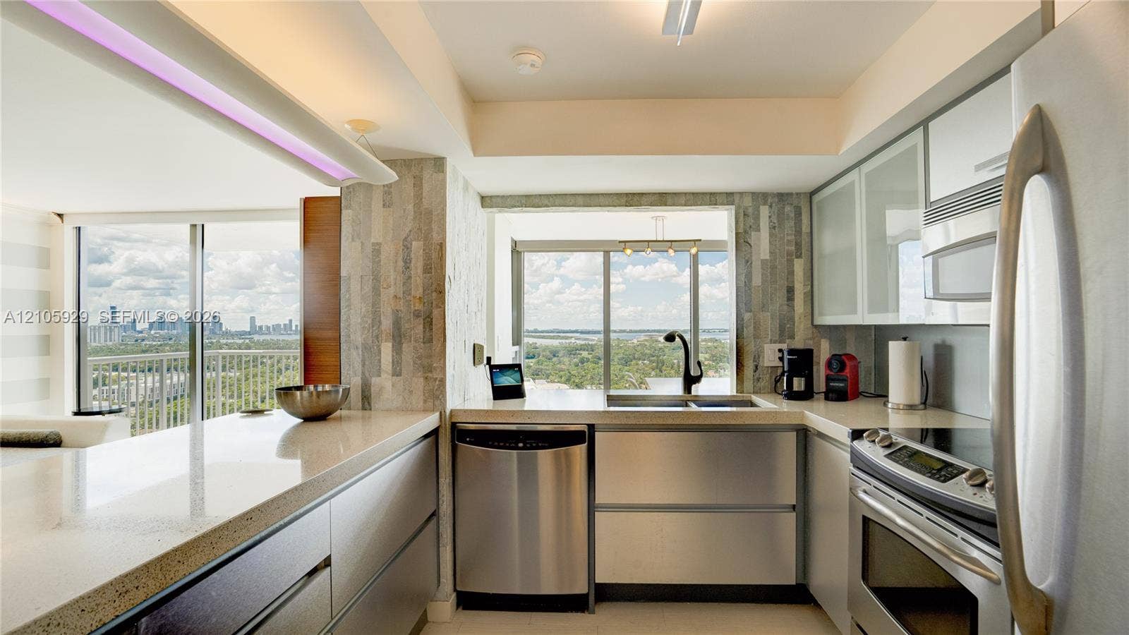 2655 Collins Avenue, #2301, Miami Beach, FL 33140 Kitchen featuring stainless steel appliances, flat-panel cabinetry with glass-front uppers, solid surface countertops, a textured stone backsplash, and floor-to-ceiling windows