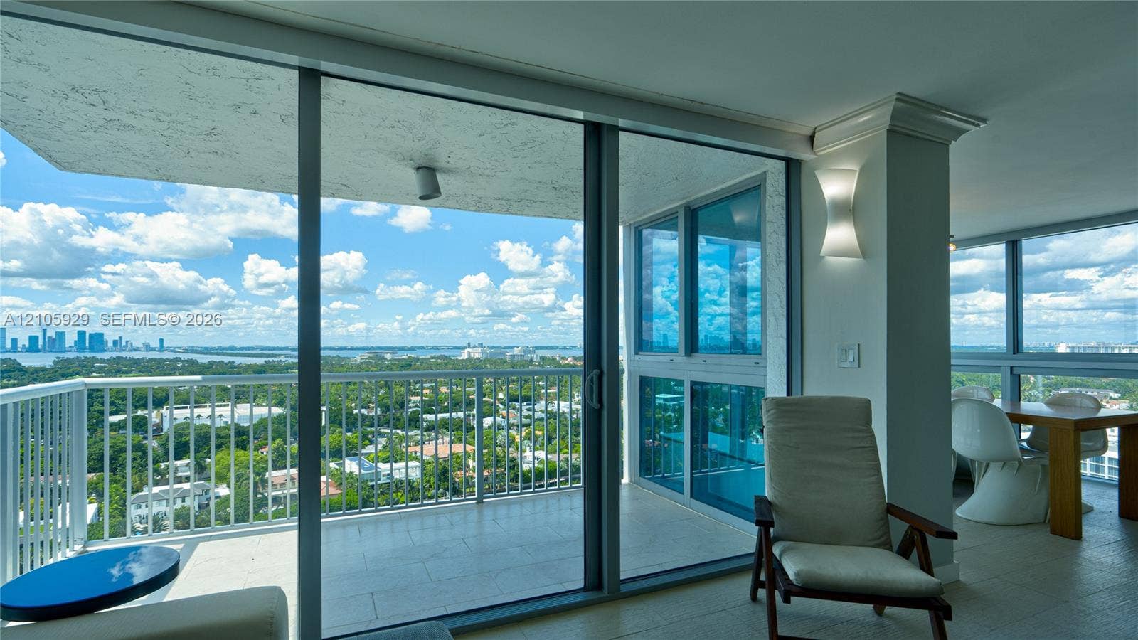 2655 Collins Avenue, #2301, Miami Beach, FL 33140 Floor-to-ceiling glass sliding doors, wrap-around covered balcony with metal railing, tile flooring, and architectural wall sconce