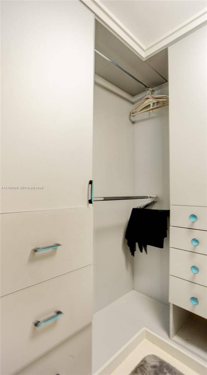 2655 Collins Avenue, #2301, Miami Beach, FL 33140 Built-in cabinetry featuring matte white finish, integrated hanging rods, and drawers with metal hardware