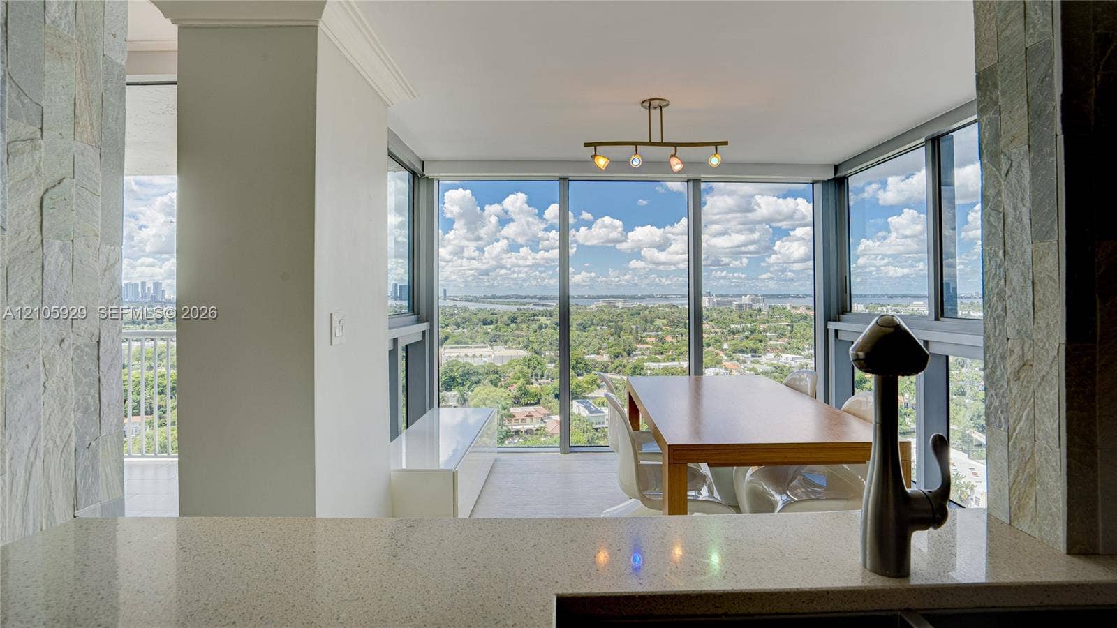 2655 Collins Avenue, #2301, Miami Beach, FL 33140 Floor-to-ceiling windows, quartz countertop, multi-light metallic fixture, stone-accented columns, and extensive cityscape scenery