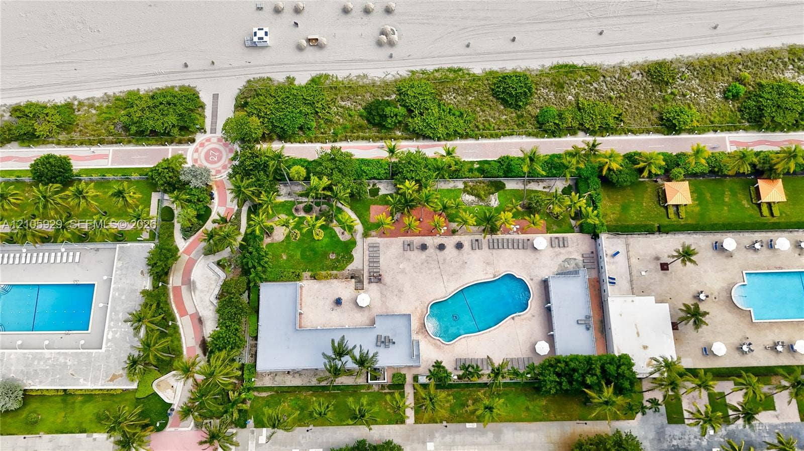 2655 Collins Avenue, #2301, Miami Beach, FL 33140 Aerial perspective featuring multiple swimming pools, paved walkways, landscaped green spaces, and direct proximity to the beach