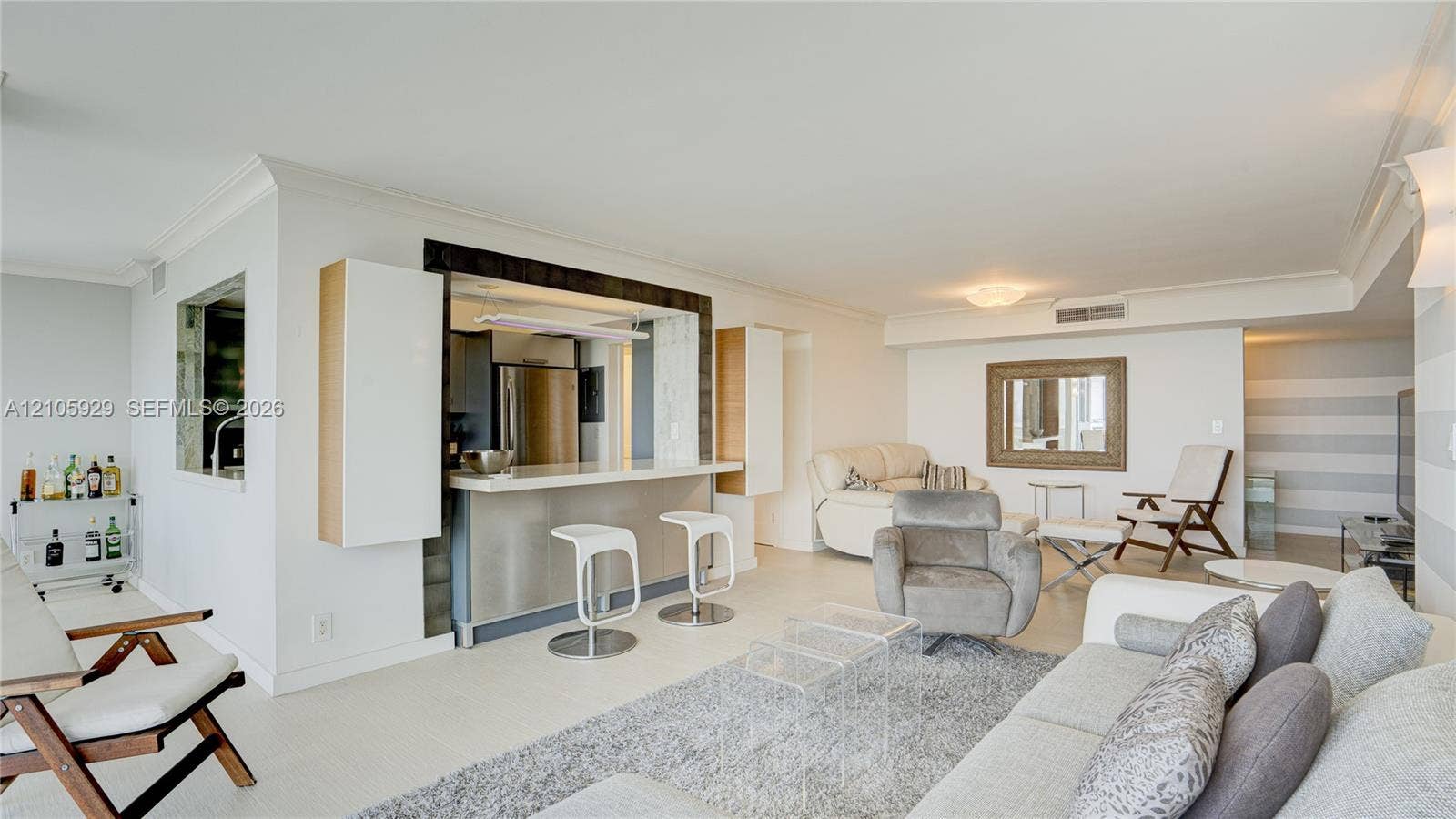 2655 Collins Avenue, #2301, Miami Beach, FL 33140 Open-concept interior featuring a breakfast bar with stone-finish countertop, crisp crown molding, recessed lighting, and a built-in cabinetry surround
