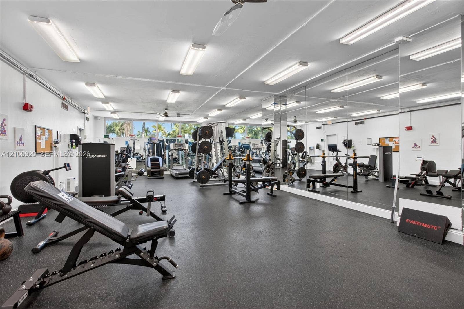 2655 Collins Avenue, #2301, Miami Beach, FL 33140 Expansive fitness area featuring floor-to-ceiling wall mirrors, durable rubberized flooring, and multiple ceiling-mounted fluorescent lighting fixtures