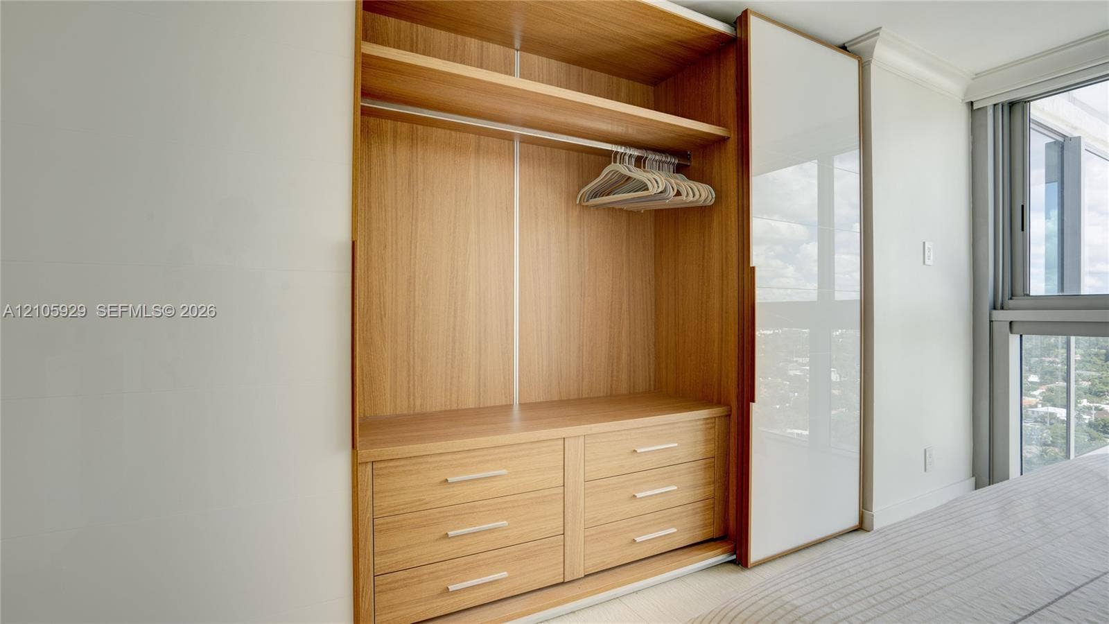 2655 Collins Avenue, #2301, Miami Beach, FL 33140 Built-in floor-to-ceiling wardrobe featuring wood-finish cabinetry, six integrated drawers, overhead shelving with a clothing rod, and a sliding glass door panel