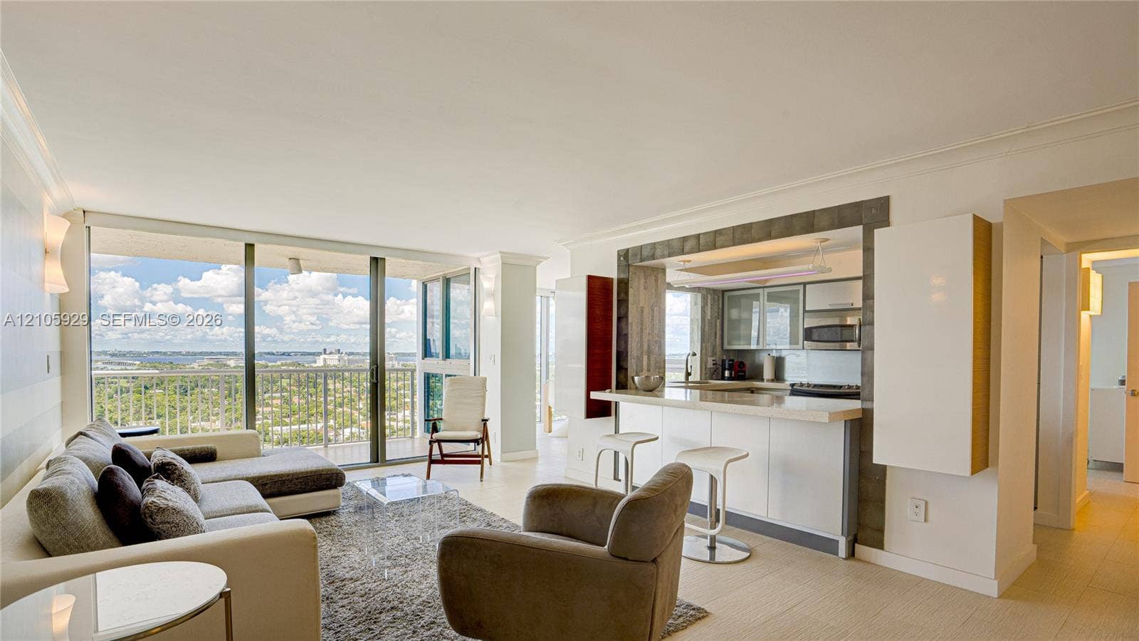 2655 Collins Avenue, #2301, Miami Beach, FL 33140 Floor-to-ceiling glass doors, open-concept kitchen with breakfast bar, built-in cabinetry, tile flooring, and expansive balcony