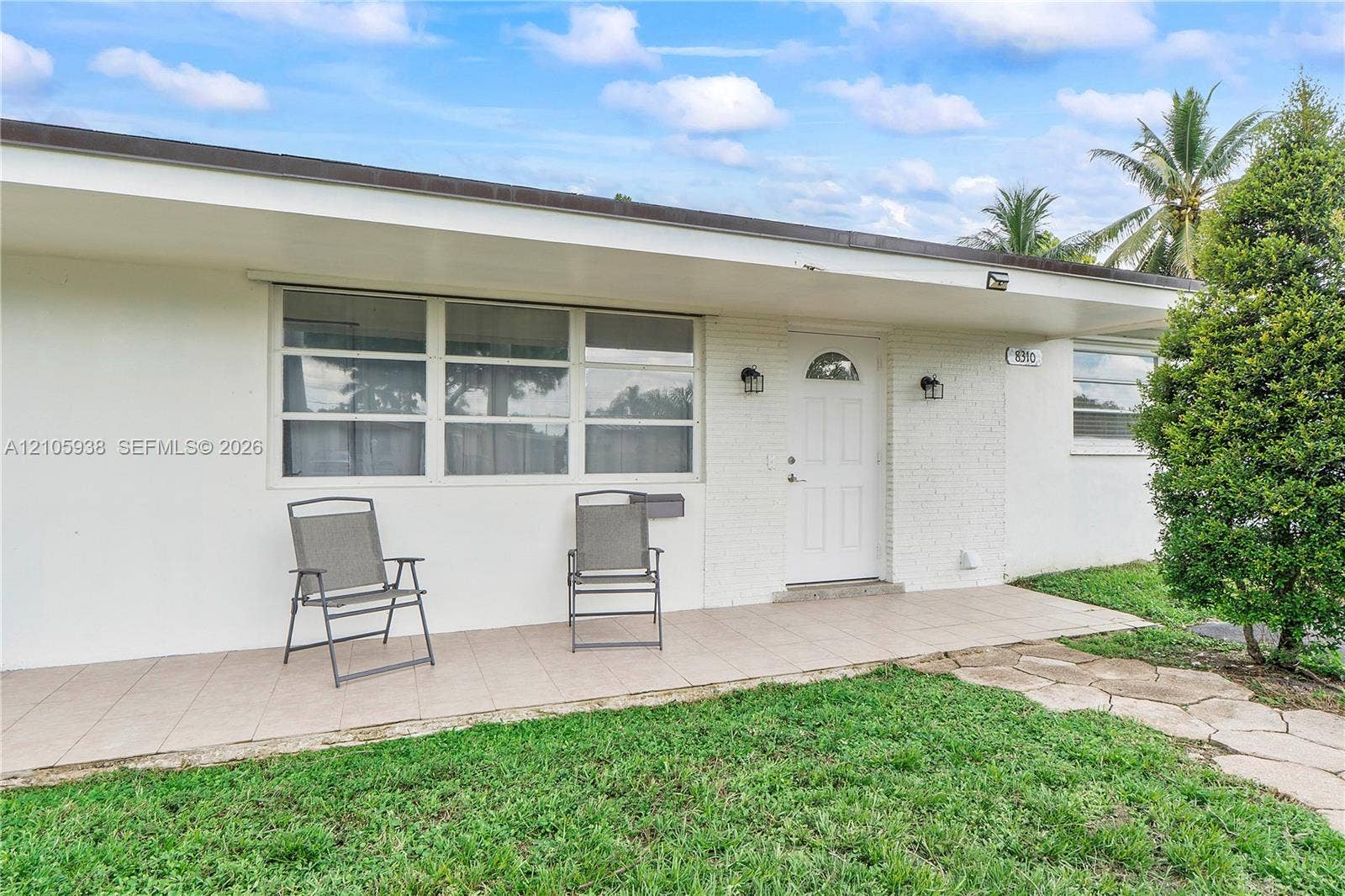 8310 NW 10th Street, Pembroke Pines, FL 33024 Exterior featuring a white painted brick facade, covered tiled entryway, multi-pane windows, and a flagstone pathway