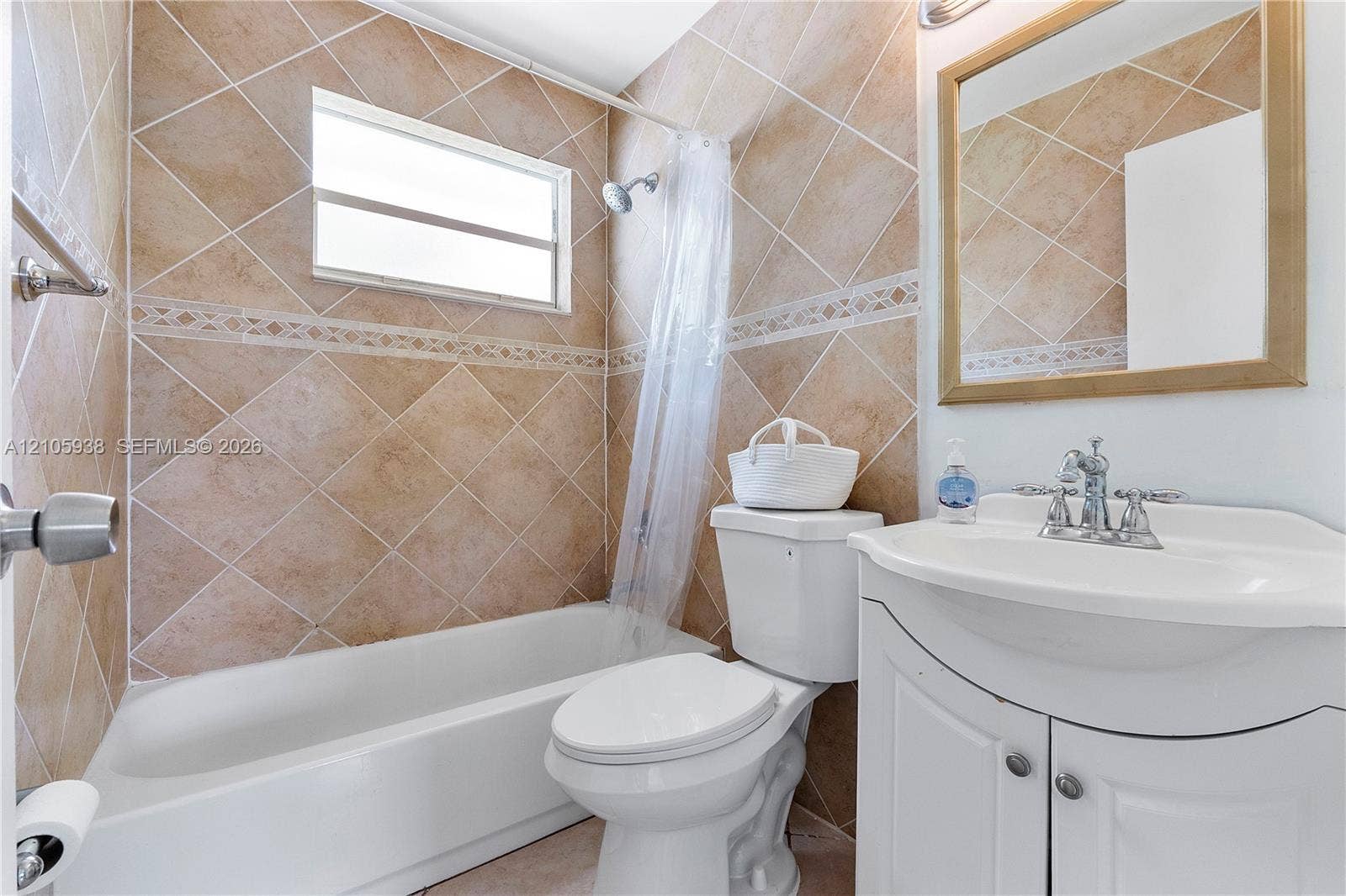 8310 NW 10th Street, Pembroke Pines, FL 33024 Bathroom featuring diamond-patterned wall tiling with decorative border inlay, porcelain tub-shower combination, and white vanity cabinet with a curved basin and chrome fixture