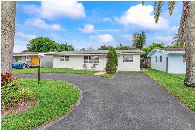 8310 NW 10th Street, Pembroke Pines, FL 33024 Single-story residence featuring a low-pitch roofline, stucco exterior, multi-pane windows, and a paved circular driveway