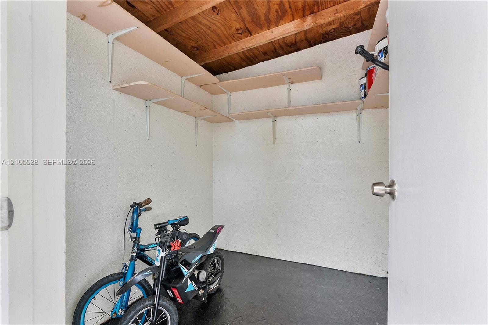 8310 NW 10th Street, Pembroke Pines, FL 33024 Storage area featuring painted concrete block walls, exposed wood ceiling rafters, and tiered wood shelving units