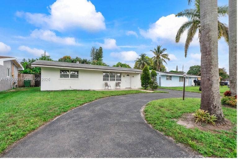 8310 NW 10th Street, Pembroke Pines, FL 33024 Single-story exterior featuring a light-toned stucco facade, a low-pitch roofline, a curved asphalt driveway, and mature palm trees within the front lawn