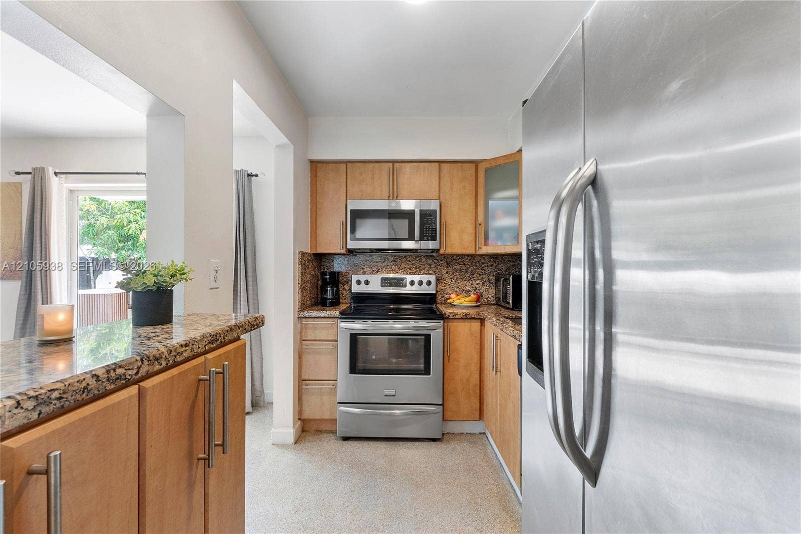 8310 NW 10th Street, Pembroke Pines, FL 33024 Kitchen featuring wood cabinetry, stone countertops, stainless steel appliances, and a breakfast bar