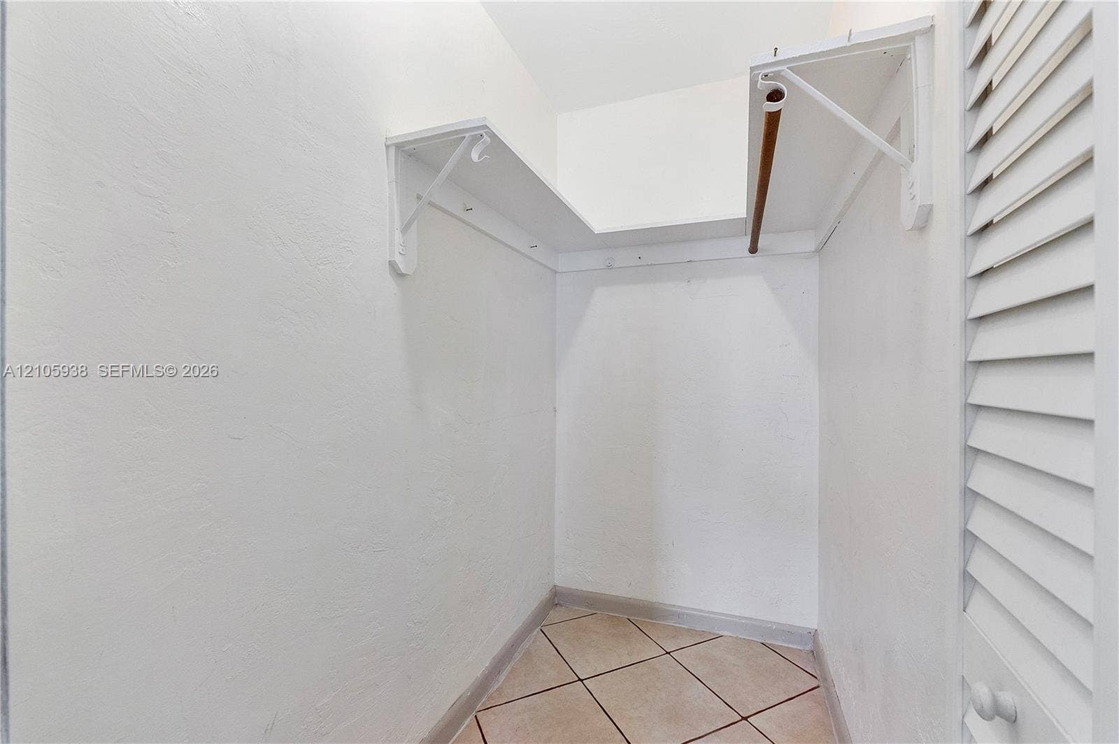 8310 NW 10th Street, Pembroke Pines, FL 33024 Storage area featuring louvered bi-fold doors, white shelving, a clothing rod, and tile flooring