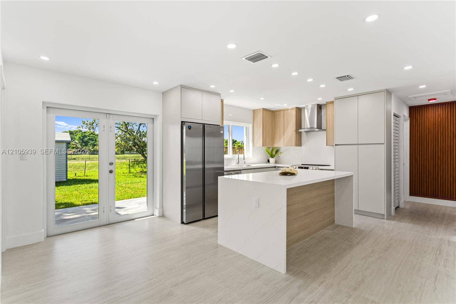 2850 NW 205th Street, Miami Gardens, FL 33056 Kitchen featuring a central island with a solid surface countertop, stainless steel refrigerator, recessed lighting, double glass doors, and tile flooring