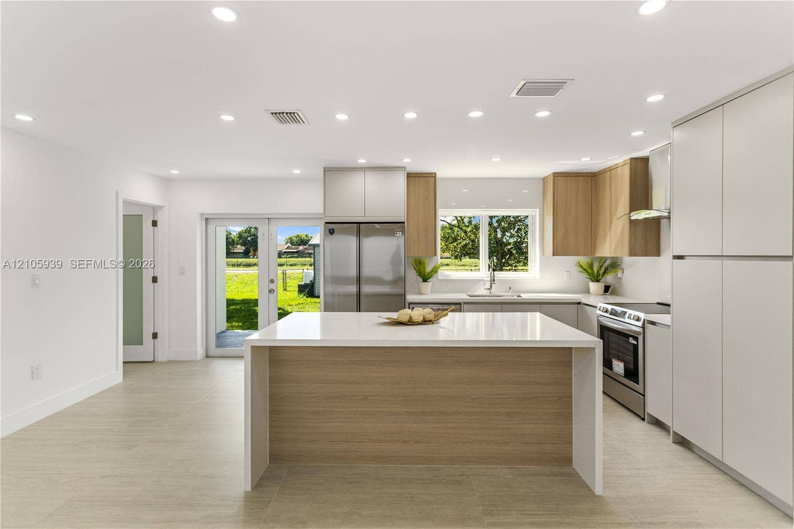2850 NW 205th Street, Miami Gardens, FL 33056 Kitchen featuring two-tone cabinetry, a central island with white stone-finish countertop, stainless steel appliances, recessed ceiling lighting, and wood-finish flooring