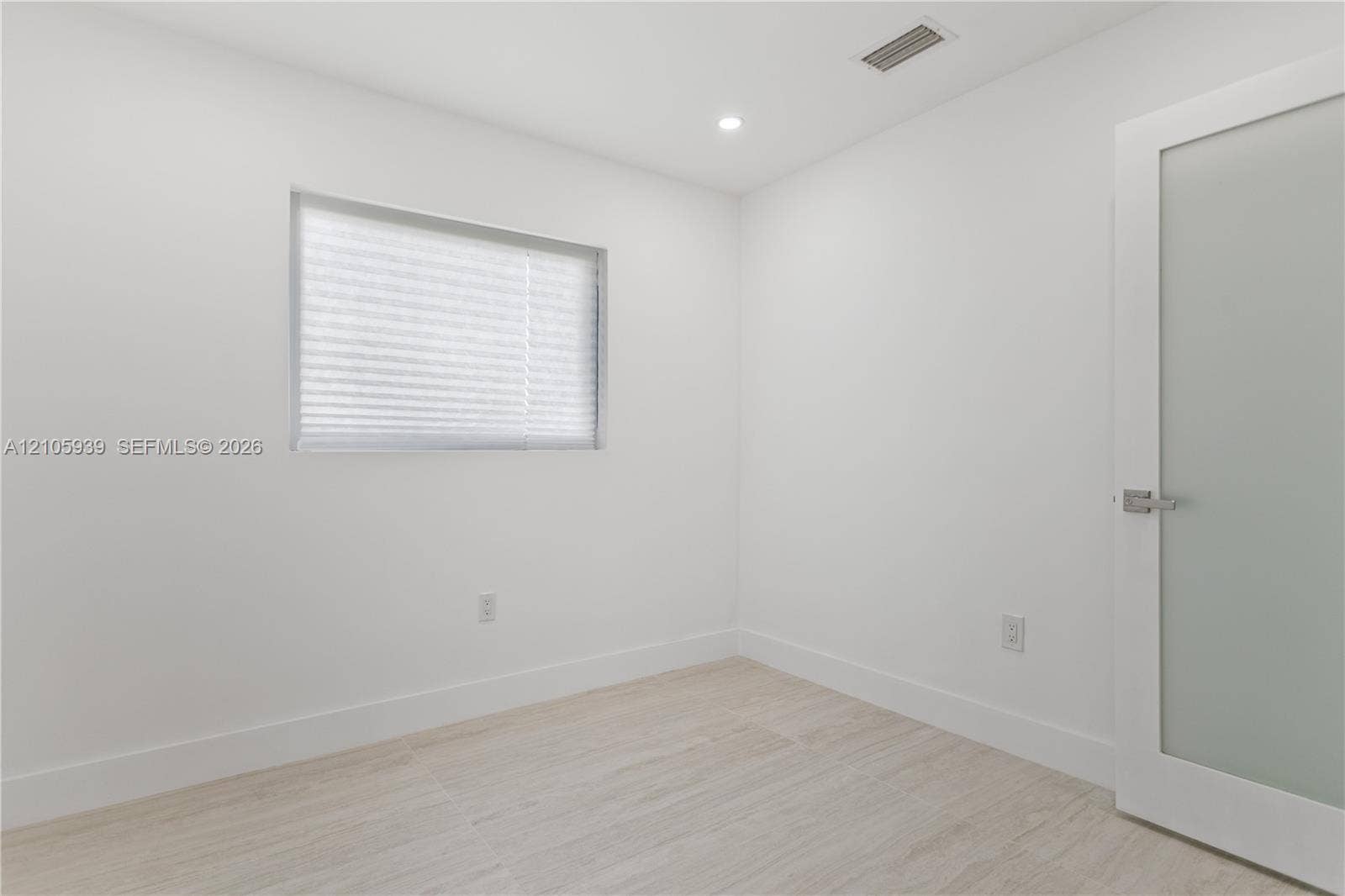 2850 NW 205th Street, Miami Gardens, FL 33056 Neutral interior space featuring wood-finish flooring, recessed lighting, and a frosted glass-panel door