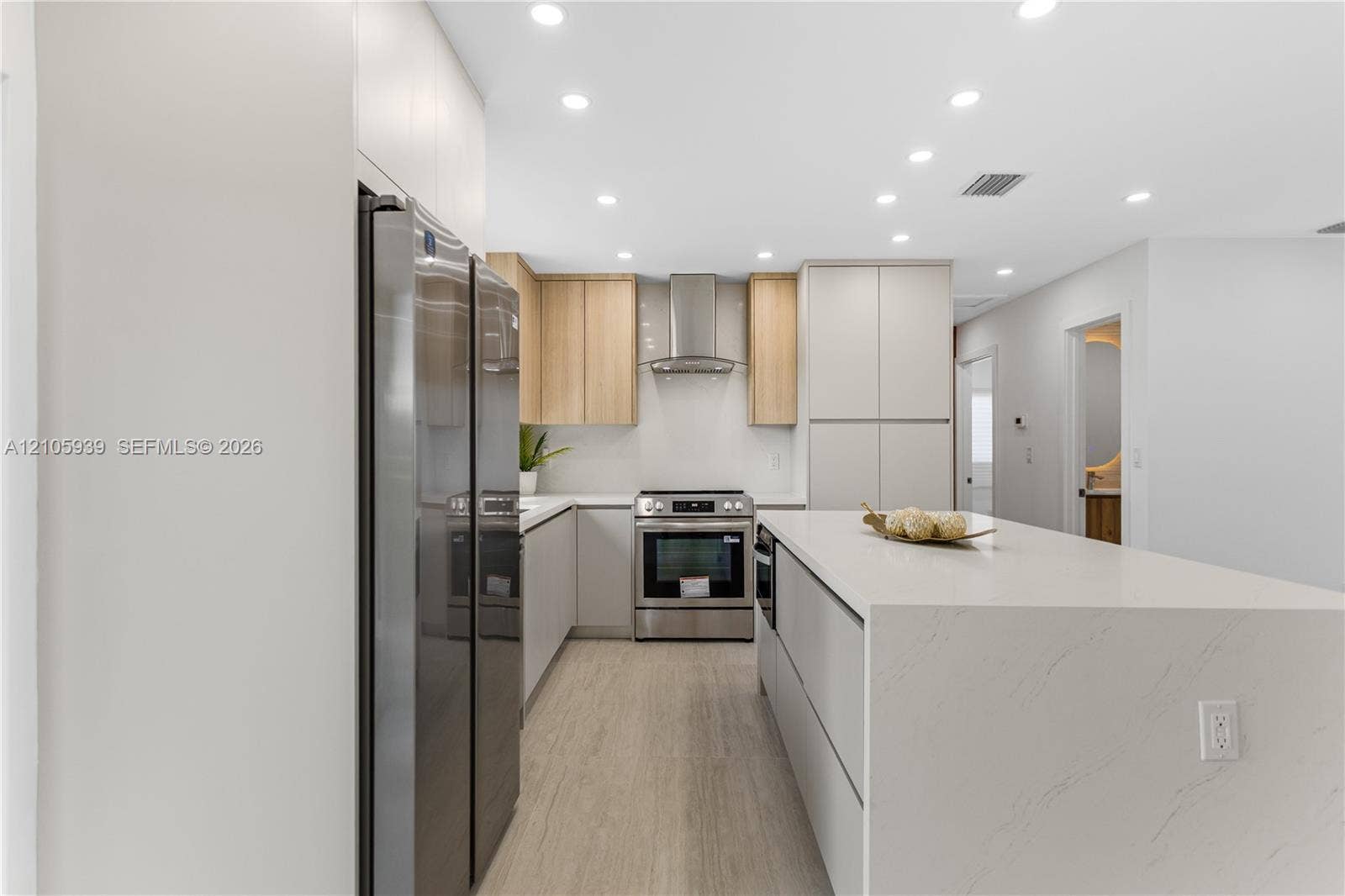 2850 NW 205th Street, Miami Gardens, FL 33056 Kitchen featuring a waterfall-edge stone island, stainless steel appliances, a modern stainless steel range hood, dual-tone cabinetry, and wood-finish flooring