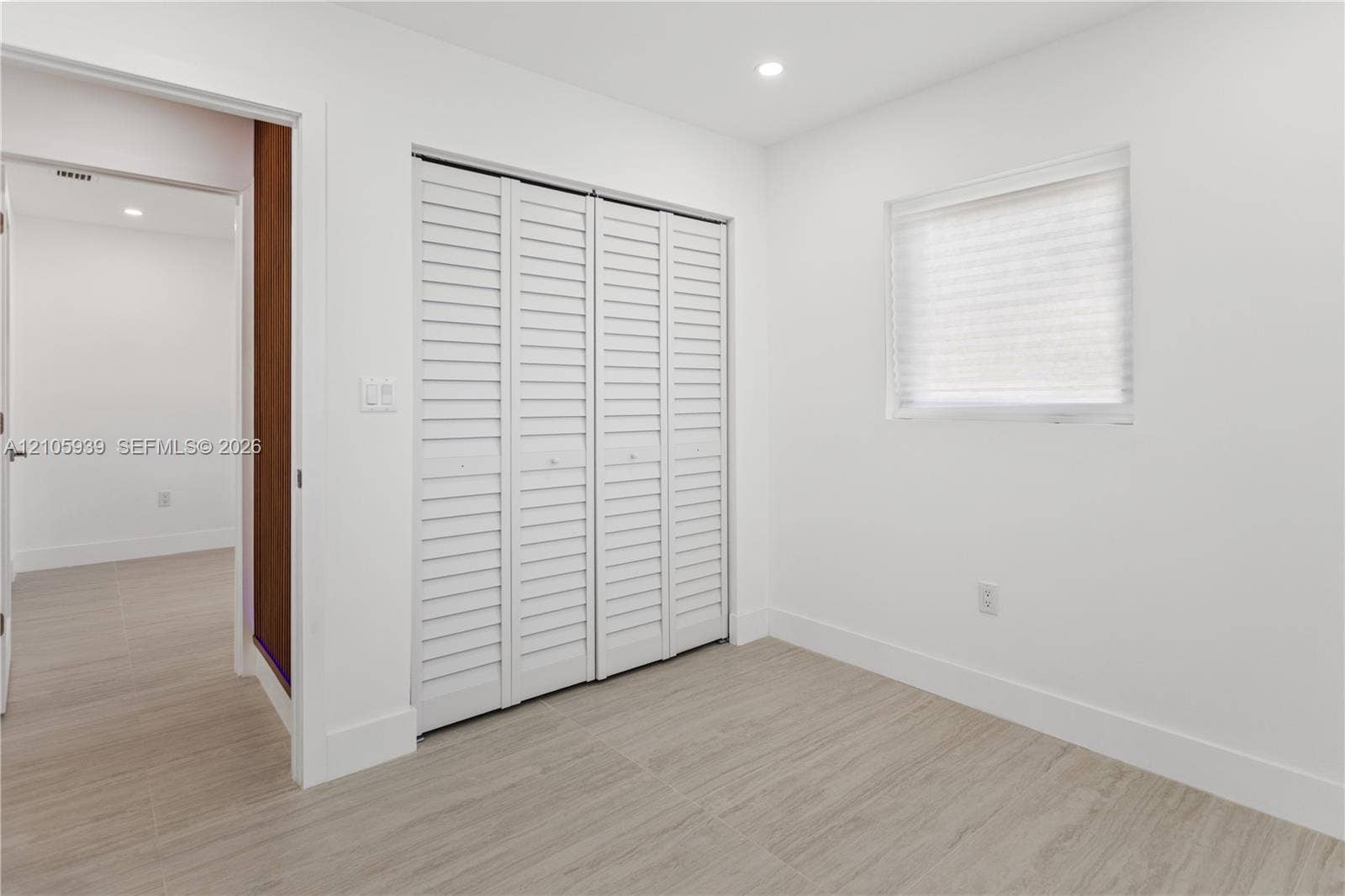 2850 NW 205th Street, Miami Gardens, FL 33056 Room featuring wood-finish flooring, white walls, louvered bi-fold closet doors, and recessed lighting